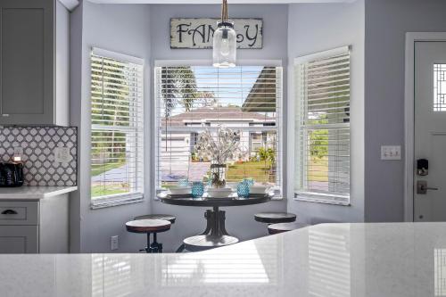 a kitchen with a table with chairs and windows at Tropical Oasis- Pickleball, Pool, Hot Tub- 15 min to beach in Melbourne