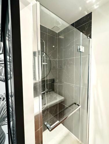 une douche avec une porte vitrée dans une salle de bain dans l'établissement Your Home Loos - Close to LILLE, à Loos