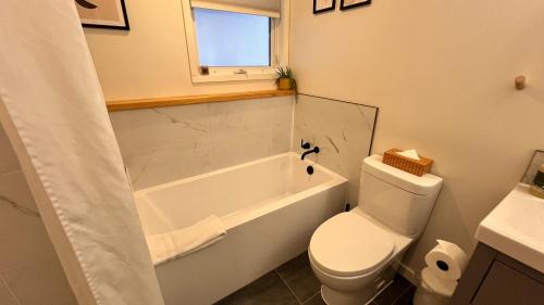 a bathroom with a tub and a toilet and a sink at 2 Bedroom Basement Suite in Fernie by StayIn in Fernie