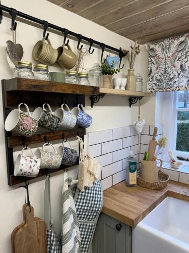 eine Küche mit vielen Töpfen und Pfannen auf Regalen in der Unterkunft Mantlemas Cottage in Turners Hill