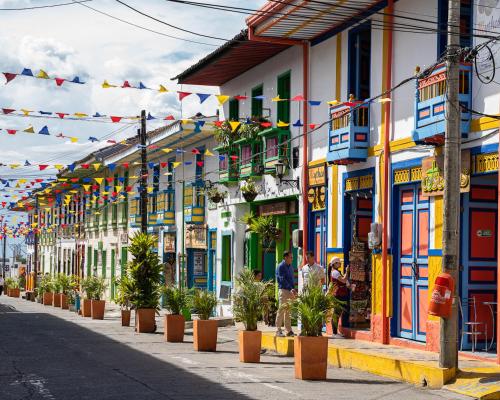 a street with colorful buildings and potted plants and flags at MuchoSur Filandia in Filandia