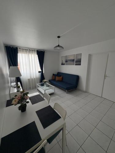 a living room with a table and a blue couch at F3 avec Projecteur à 2 min du métro in Saint-Ouen