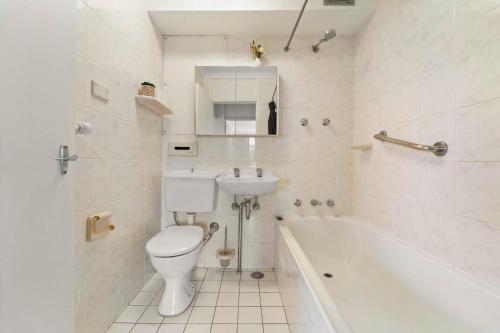 a bathroom with a toilet and a sink and a tub at Harbourside 10 in Sydney