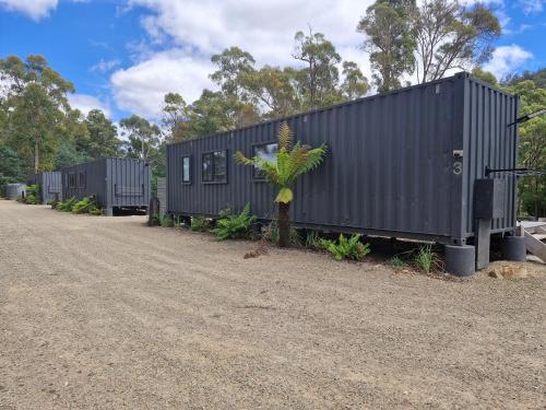 a row of black shipping containers on a dirt road at Rail Trail Retreat in Scottsdale