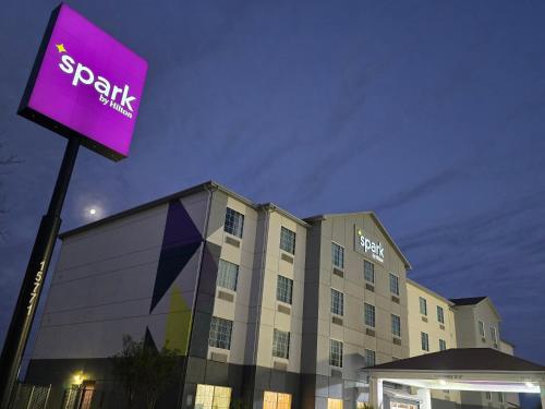 a hotel with a purple sign in front of a building at Spark by Hilton Selma in Selma