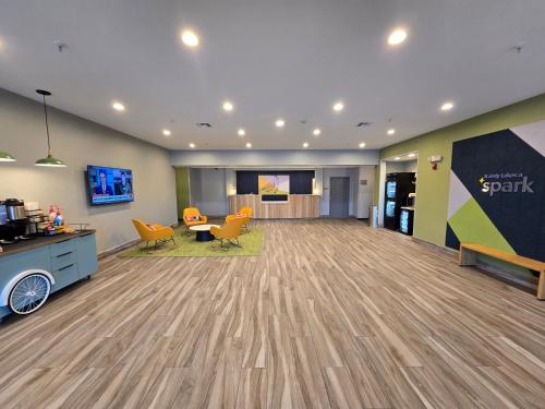 a large lobby with a waiting area with orange chairs at Spark by Hilton Selma in Selma