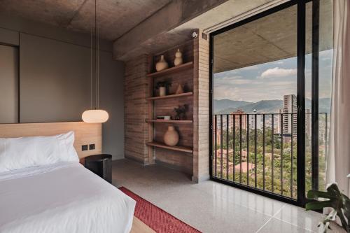 a bedroom with a bed and a large window at The Somos Loho Hotel in Medellín