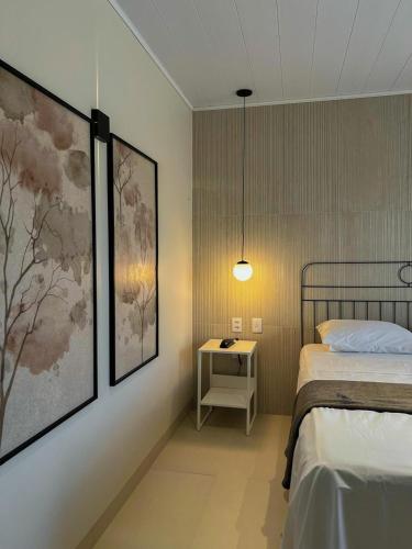 a bedroom with a bed and a table with a night stand at Hotel Flor de Lis in Brejo Santo