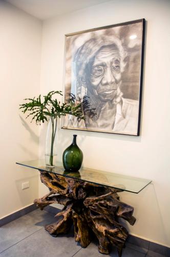 a table with a vase and a painting on a wall at Hotel Las Cascadas in San Pedro Sula