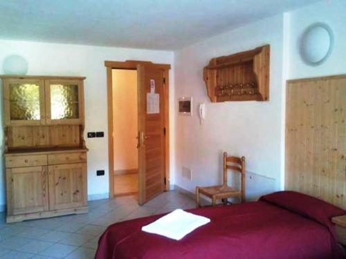 a bedroom with a red bed and a wooden cabinet at Hotel Residence Bellavista - Camping Polsa in Brentonico