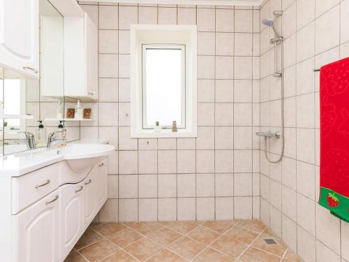a white bathroom with a sink and a window at 8 person holiday home in Jerup in Jerup