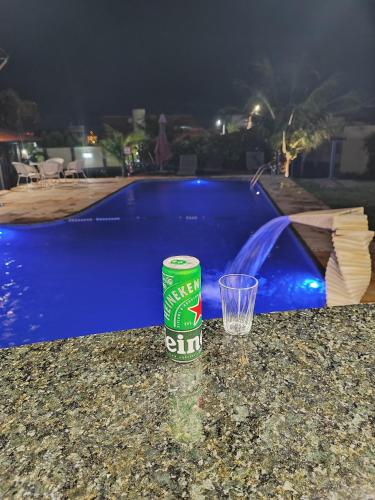 a bottle and a glass sitting on a table next to a pool at Pousada Vila Italia - Porto da Dunas in Aquiraz