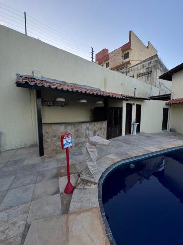 a swimming pool with a sign in front of a house at Pousada Vila Italia - Porto da Dunas in Aquiraz