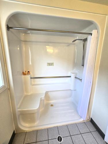 a walk in shower in a bathroom with a white at Breeze Inn Hotel in Seward