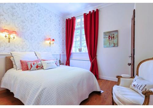 - une chambre avec des rideaux rouges, un lit et une chaise dans l'établissement Charmant T3 Mont des Oiseaux 3 Etoiles - HYERES - Vue mer - Tennis, à Hyères