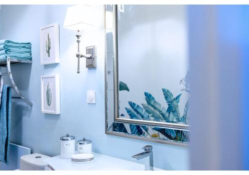 La salle de bains bleue est pourvue d'un miroir et d'un lavabo. dans l'établissement Charmant T3 Mont des Oiseaux 3 Etoiles - HYERES - Vue mer - Tennis, à Hyères