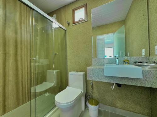 Un baño con inodoro, lavabo y ducha. en Bela acomodação em jacuipe com churrasqueira, piscina, mesa de sinuca e três quartos, dois sendo suítes! Além de muito espaço por toda a área!, en Barra do Jacuípe