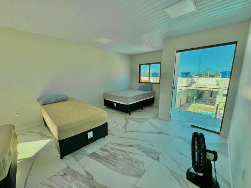 Un dormitorio con dos camas y una gran ventana. en Bela acomodação em jacuipe com churrasqueira, piscina, mesa de sinuca e três quartos, dois sendo suítes! Além de muito espaço por toda a área!, en Barra do Jacuípe