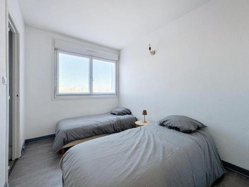 deux lits dans une chambre blanche avec une fenêtre dans l'établissement Le balcon, à Dunkerque