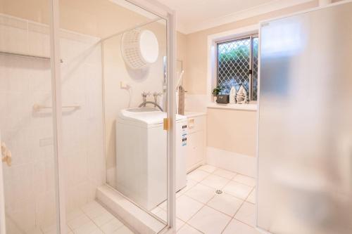a white bathroom with a shower and a sink at Bushmans, 9 24 Tomaree Street - Spacious townhouse with air conditioning and close to Nelson Bay Town Centre in Nelson Bay