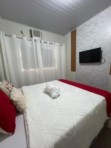 a bedroom with a white bed with a tv on the wall at VILINHA LOFT HOME - AP 03 - TÉRREO - Excelente Localização in Cuiabá