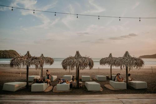 a group of people sitting under umbrellas on the beach at LUXURY Apartment in BLUE Playa Venao B-32 in Playa Venao
