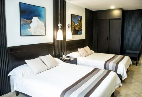 a hotel room with two beds in a room at Hotel Las Cascadas in San Pedro Sula