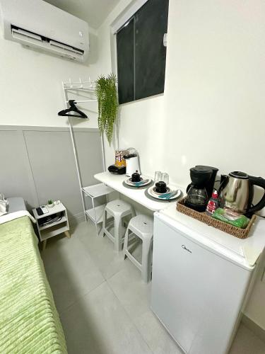 une cuisine blanche avec un comptoir et une table dans l'établissement Suítes Encanto do Mar, à Arraial do Cabo