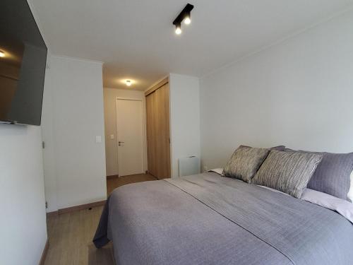 - une chambre avec un grand lit et une couverture grise dans l'établissement Modern Apartamento con Suites - Centro de Temuco, à Temuco