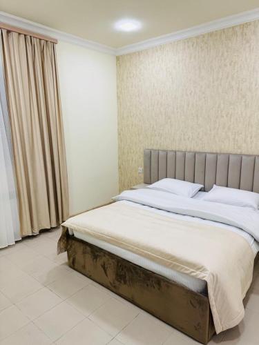 a bedroom with a large bed with white sheets at Lux Plaza Hotel EVN airport in Arbatʼ