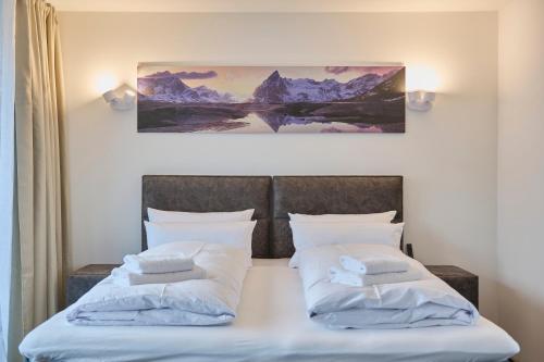 a bed with two pillows and a painting on the wall at TROPICAL ISLAND 23C - Seesicht - Massage - BBQ - Billiard - Tischkicker - Penthouse - Parkplatz in Öhningen