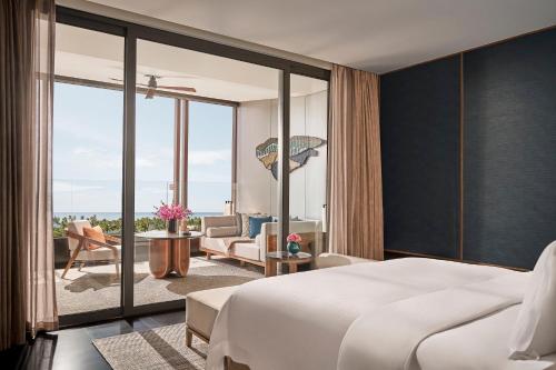 a bedroom with a large white bed and a balcony at Regent Phu Quoc in Phu Quoc