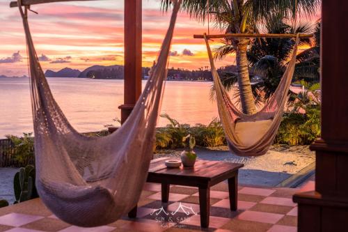 two hammocks on a patio with a table and the ocean at Sun and Sand Beachfront Pool Villa in Koh Phangan