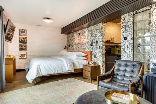a bedroom with a bed and a chair and a table at The Reed at The Louie Boutique Motel, Private Sauna! Walk to Everything! in Newport