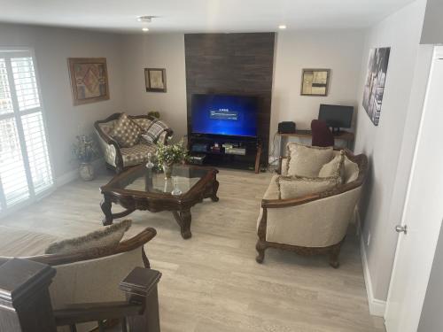 a living room with a tv and chairs and a table at Country in the City - Wonderful Complimentary Breakfast Delivered Daily to House in Niagara Falls