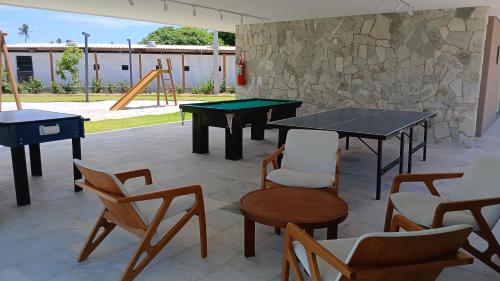 a patio with two ping pong tables and chairs at MALIA MURO ALTO STUDIO 300m DO MAR in Porto De Galinhas
