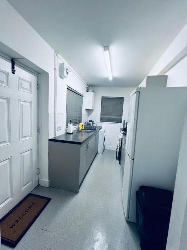 a kitchen with a white refrigerator and a door at SwankyHome4Groups NearM6 in Walsall