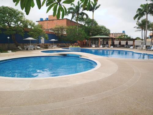 a swimming pool in a resort with tables and chairs at Apartamento Punta Brava en el Centro de Tucacas in Tucacas