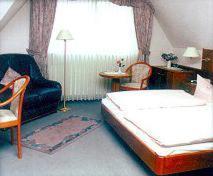 a bedroom with a bed and a chair and a couch at Hotel zur Struth in Eschwege
