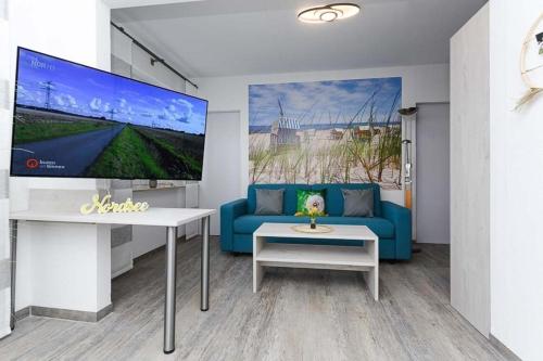 Una sala de estar con un sofá azul y un televisor. en Strandkorb 4, en Bensersiel