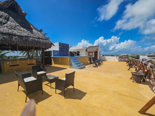 a patio with chairs and tables and a thatched roof at Hotel Villas Ponto Holbox in Holbox Island