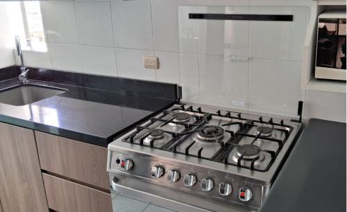 a stove top oven in a kitchen next to a sink at El Derby 511 Aparts de 3 Dorm con Aire Acondicionado in Lima