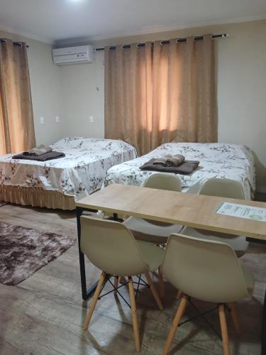 a room with two beds and a table and chairs at Loft Confort in Pomerode