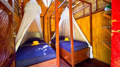 two beds with drapes in a room at Sten Lodge in Labuan Bajo