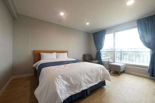 a bedroom with a bed and a large window at Sweet Stay Pension in Seogwipo