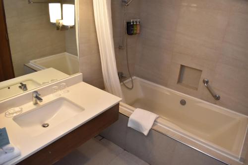 a bathroom with a sink and a bath tub at Holiday Inn & Suites Batangas LimaPark by IHG in Batangas City