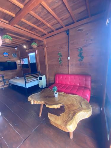 ein Wohnzimmer mit einer roten Couch und einem Holztisch in der Unterkunft Noah's Ark Homestay in Timuran