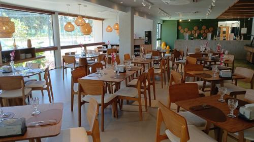 a restaurant with wooden tables and chairs and windows at MALIA MURO ALTO STUDIO 300m DO MAR in Porto De Galinhas