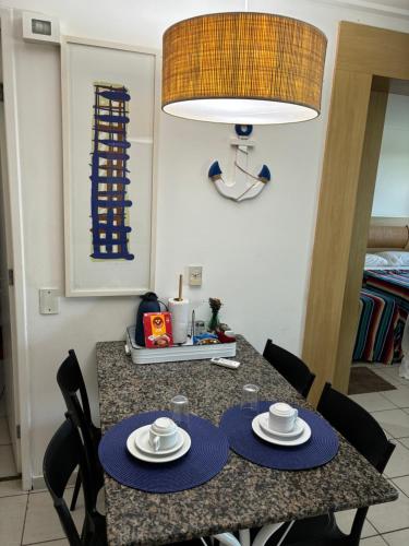 a dining room table with two plates and a lamp at Flat Beach Class Resort Muro Alto in Porto De Galinhas
