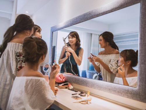 a woman taking a picture of herself in a bathroom mirror at Hotel Torifito Naha Asahibashi in Naha